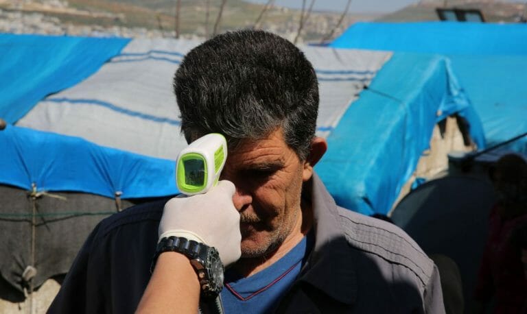 Mitarbeiter einer NGO misst in einem Flüchtlingslager in Idlib Fieber