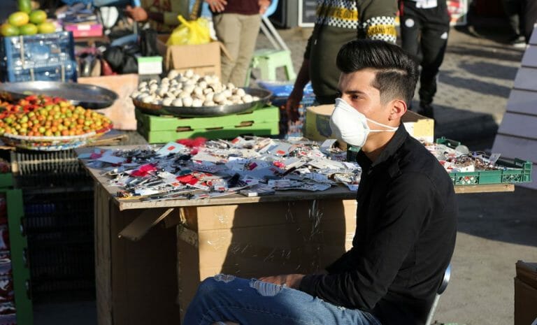 Verkäufer auf Markt in Bagdad mit Corona-Maske