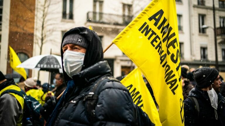 Demonstrant mit einer Flagge von Amnesty International