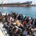 Mitglieder der libyschen Küstenwachen mit Flüchtlingen aus Subsahara-Afrika